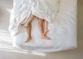 Top view of romantic couple sleeping. bare feet of their legs lying in a bed with white blanket in love and sex concept in modern Royalty Free Stock Photo