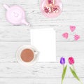 Top view of a romantic scene of a cup of tea, a tea pot, flowers and an empty sheet of paper on a wooden background. Background or Royalty Free Stock Photo