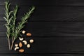 Top view of rosmarin leafs and nuts on black wooden background.