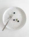 Top view of round white ceramic plate with fork, Dirty dishe after eating blueberry cheese tart is finished. Royalty Free Stock Photo