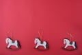 Top view of a row of beautiful wooden Christmas toys of snow-white rocking horses on golden pendants.
