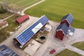 Top view of rural landscape on sunny spring day. Farm with solar photo voltaic panels system on wooden building, barn or house