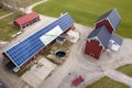 Top view of rural landscape on sunny spring day. Farm with solar photo voltaic panels system on wooden building, barn or house