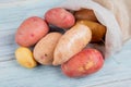 top view of russet new and red potatoes spilling out of sack on wooden background Royalty Free Stock Photo