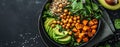 Top view of a salad with avocado, quinoa, sweet potato, spinach, chickpeas in a black bowl Royalty Free Stock Photo