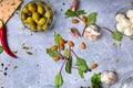 A top view of salad ingredients. Green stuffed olives in a glass bowl next to almond nuts and salad leaves on a gray Royalty Free Stock Photo