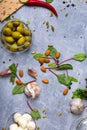 A top view of salad ingredients. Green stuffed olives in a glass bowl next to almond nuts and salad leaves on a gray Royalty Free Stock Photo