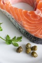Top view of salmon slice with parsley and capers on white plate