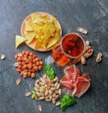 Top view of salty snacks and dark beer on a black background. Peanuts, pistachios, ham and basil with a glass of beer Royalty Free Stock Photo