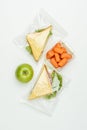 top view of sandwiches in ziplock bags and carrots in lunch box on white