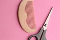 Top view of scissors and a wooden comb on a pink background Royalty Free Stock Photo