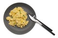 Top view of scrambled eggs with fresh green chives on dark grey plate with elegant cutlery isolated on white background Royalty Free Stock Photo