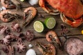 Top view of seafood banner with crab, shrimps, octopuses, lime, lemon, seashells and sea salts on rustic wooden background.