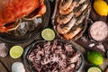 Top view of seafood. Plates with cooked king crab, shrimps and baby octopuses served with lime, sea salt, seashells on rustic