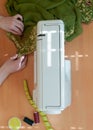 Seamstress hands tailoring green cloth with white sawing machine at wooden table in studio Royalty Free Stock Photo