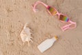 Top view of seashell swimming goggles and sunscreen lotion on sand. Royalty Free Stock Photo