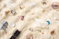 Top view of seashells, bottle caps, scattered cigarette butts, plastic cups, glass bottle and candy wrapper on sand. Royalty Free Stock Photo