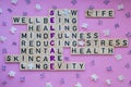 Top view of SELFCARE word on pink background with flowers. Minimalism creative crossword puzzle concept. Message of text