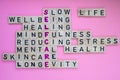 Top view of SELFCARE word on pink background. Minimalism creative crossword puzzle concept. Message of text Slow life