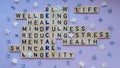 Top view of SELFCARE word on purple background with flowers. Minimalism creative crossword puzzle concept. Message of