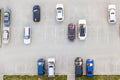 Top view of a semi-empty asphalt parking lot with black white and blue cars parked near a residential building on a summer day Royalty Free Stock Photo