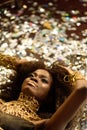 Top view of sensual attractive young woman with gold lips lying on background shining confetti Royalty Free Stock Photo
