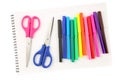 Top view of a set of colorful felt tip pens and two scissors on a blank, opened sketchbook sheet, isolated on white background. Royalty Free Stock Photo