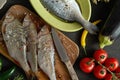 Top view of a set of fresh, raw fish in various dishes and with vegetables on a black table Royalty Free Stock Photo