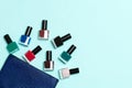 Top view of the set of nail polishes and bright gel varnishes fallen out of cosmetics bag with copy space on blue background. Royalty Free Stock Photo