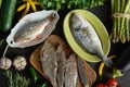 Top view of a set of fresh, raw fish in various dishes and with vegetables on a black table Royalty Free Stock Photo