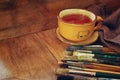 Top view of set of used paint brushes, cup of hot tea and palette over wooden table Royalty Free Stock Photo