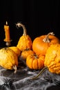 Top view of several orange halloween pumpkins and burning candle, on table with spiders and spider web, black background, Royalty Free Stock Photo