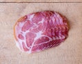 Top view of several slices in a row of dry coppa on an old wood cutting board