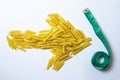 Top view in the shape of an arrow from raw pasta indicates a measuring tape on a white background