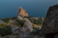 top view of sharp rocks cliff among green trees on the shore, coast of blue sea, Crimea, summer, sunset Royalty Free Stock Photo