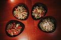Top view shot of four bowls of salads with meat and vegetables