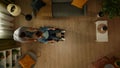 Top view shot of a man helping a disabled adult, a woman with mobility impairment navigate around the room on a