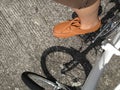 Man who wears brown pants and leather shoe is riding white bicycle