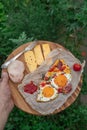 Top view shot of Strammer Max, tomato, cheese, fork and sauce on wooden plate in male hand