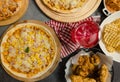 Top view shot of various kinds of delicious tasty juicy cheesy pizza placed on wooden board on party table around with other fast