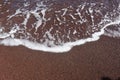 Top view shot of white salty bubbles waves on the sandy shore