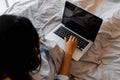 Top view shot of young girl sitting on a bed in the morning using a laptop computer to work from home and showing a Royalty Free Stock Photo