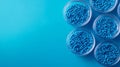 The top view shows three glass cups loaded with blue polypropylene granules, masterbatch polymer grain, on a blue background with Royalty Free Stock Photo