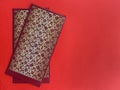 Top view side view of two dark red and golden color Chinese New Year envelopes with red background.