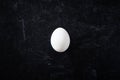 Top view of simple organic white egg on dark moody background. Royalty Free Stock Photo