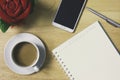 Simple workplace with a cup of coffee, notebook paper, pen, smartphone and glasses on wood table Royalty Free Stock Photo