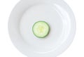 Top view of single fresh cucumber slice on white plate isolated on white background Royalty Free Stock Photo