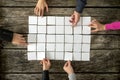 Top view of six hands, male and female, assembling a collage of