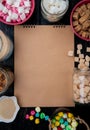 Top view of a sketchbook with various types of sugar and candies in bowls and glass jars arranged around on rustic background Royalty Free Stock Photo