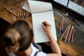 Top view on sketchbook on wooden table in which young woman draws